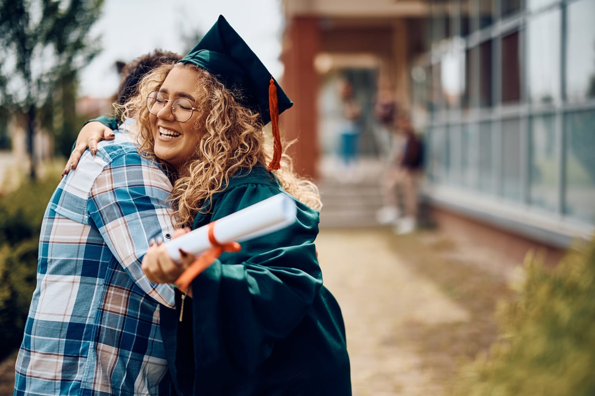 Papá abrazando con orgullo a su hija el día de su graduación universitaria